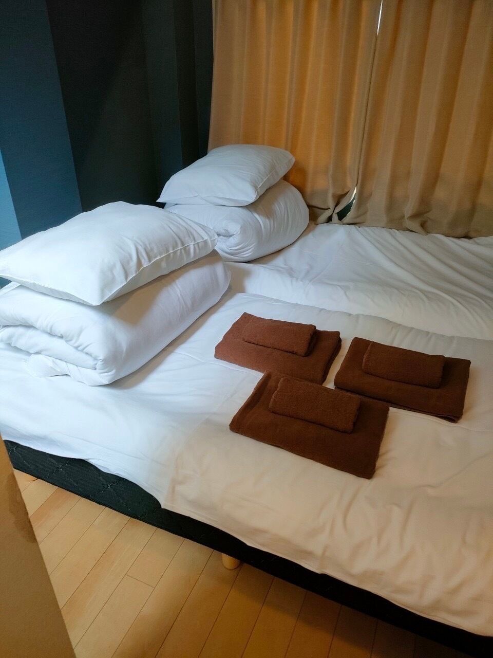 A bed with white linens and brown towels.