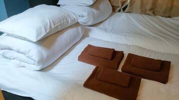 A bed with white linens and brown towels.