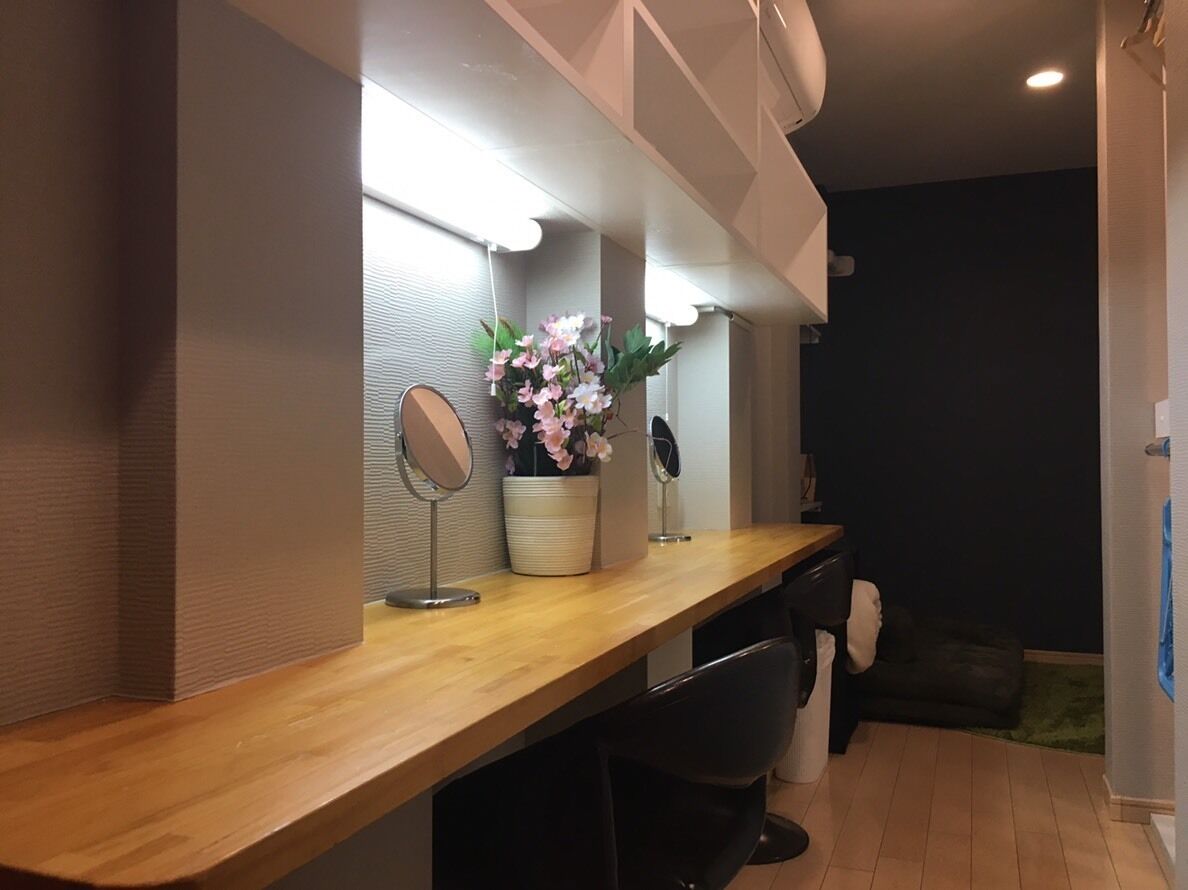 A room with a wooden desk, a mirror, a potted plant, and a chair.