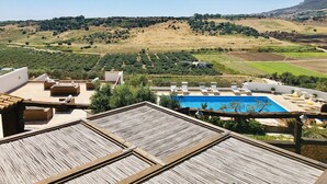 Una terrazza sul tetto con piscina, lettini e vista sulla campagna circostante.