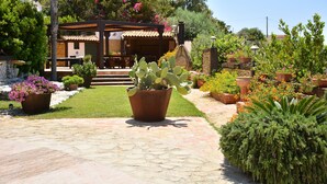 Un giardino con una pergola, piante in vaso e un vialetto in pietra.