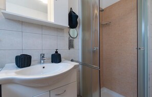A bathroom with a white sink, a mirror, a shower, and a towel rack. - 2 bedroom stunning home in Sisan (Sisan)