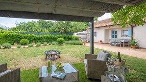 An outdoor patio area with wicker furniture, a glass table, and a fire pit. - 2 bedroom stunning home in Sisan (Sisan)