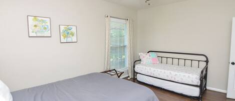 A bedroom with a bed, a ceiling fan, and two framed floral artworks on the wall.