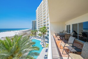 Un balcon d’hôtel avec vue sur une plage, une piscine et une jetée.