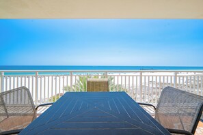 Un balcon avec vue sur la plage, une table et deux chaises.