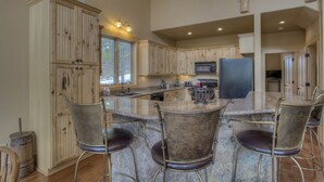 A spacious kitchen with wooden cabinets, a large island with bar stools, and a microwave. - Luxury Cabin - views, location, perfect for families, 4 miles from Breckenridge (Blue River)