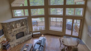 A spacious living room with a stone fireplace, large windows, a wooden deck, and a cozy seating area. - Luxury Cabin - views, location, perfect for families, 4 miles from Breckenridge (Blue River)
