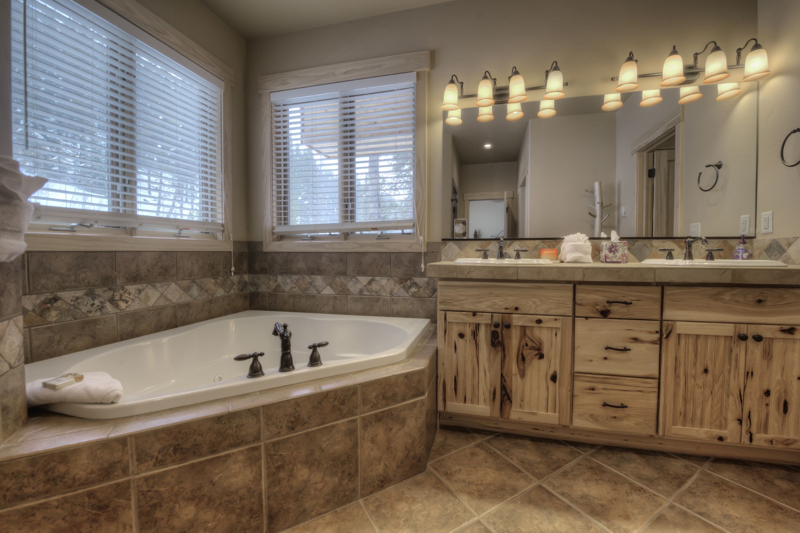 A modern bathroom with a large bathtub, wooden vanity, and a mirror with lights.