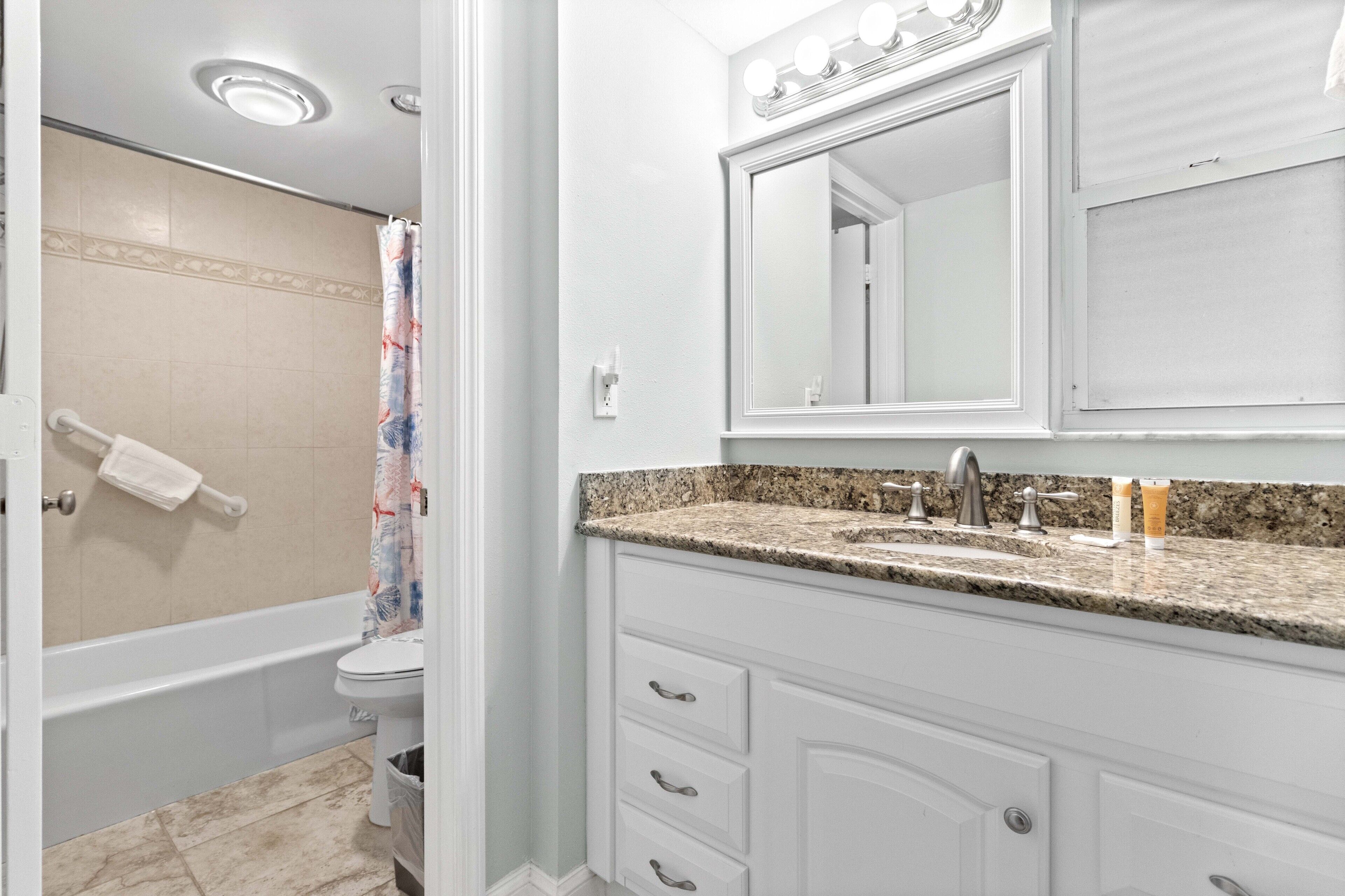 Une salle de bain équipée d’une baignoire, de toilettes et d’un lavabo, avec un miroir au-dessus.