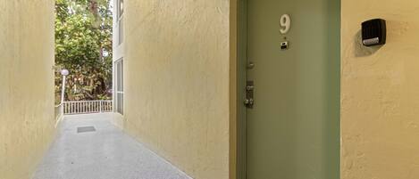 Um corredor estreito que leva a uma porta verde com o número 9.