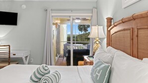 Una habitació d'hotel amb un llit, escriptori, cadira, televisió i vistes al balcó exterior.