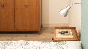 Un dormitorio con cama, armario de madera, mesita de noche con lámpara y pared azul.