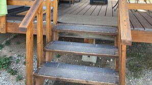 Um deck de madeira com uma escada que leva a um alpendre coberto.