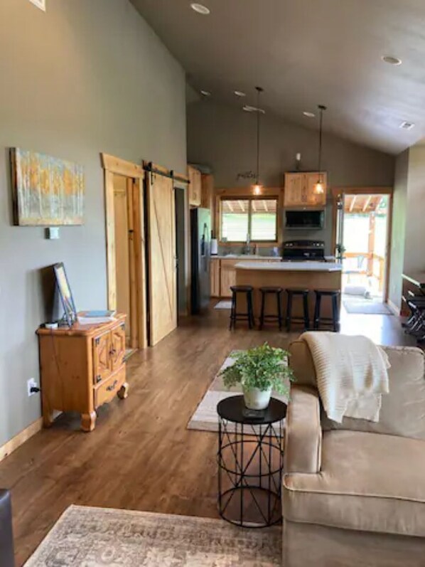 A spacious living area with a sofa, a coffee table with a plant, and a wooden cabinet.