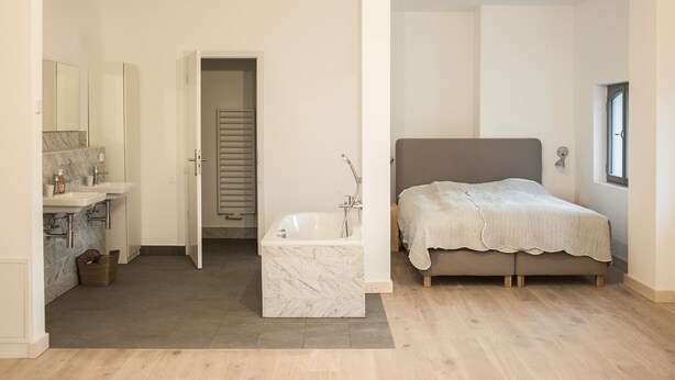 A modern bathroom with a bathtub, a vanity with a mirror, and a shower area. - Apartment Gut Üselitz on Rügen - 2. Upper floor right 1 (Poseritz)