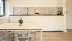A modern kitchen with white cabinets, a marble backsplash, and a wooden countertop. - Apartment Gut Üselitz on Rügen - 2. Upper floor right 1 (Poseritz)