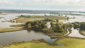 A large, open landscape with a prominent white building surrounded by water bodies and greenery. - Apartment Gut Üselitz on Rügen - 2. Upper floor right 1 (Poseritz)