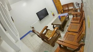 Ein Zimmer mit Fernseher, Holzmöbeln und Fliesenboden.