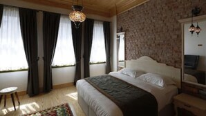 Une chambre avec un grand lit, un plafond en bois, un mur à motifs et une fenêtre avec des rideaux.