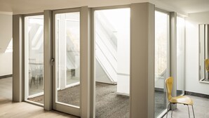 Un intérieur moderne avec de grandes portes-fenêtres coulissantes donnant sur un balcon, une chaise en bois et un escalier.