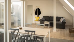 Un salon moderne avec un coin repas, un canapé gris et un fauteuil jaune.