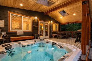A hot tub area with wooden decking, a covered seating area, and a view of the outdoors.