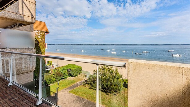 A balcony with a view of the sea, a paved path, and some greenery.