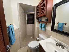 Un baño con inodoro, lavamanos y zona de ducha.