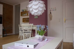 A room with a white desk, a chair, a white lamp, and a vase with flowers.