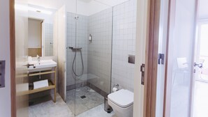 Ein modernes Badezimmer mit Duschkabine aus Glas, Waschbecken mit Handtuchhalter und Toilette.