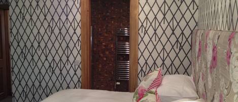 Un dormitorio con cama, mesita de noche, lámpara y pared con diseño.