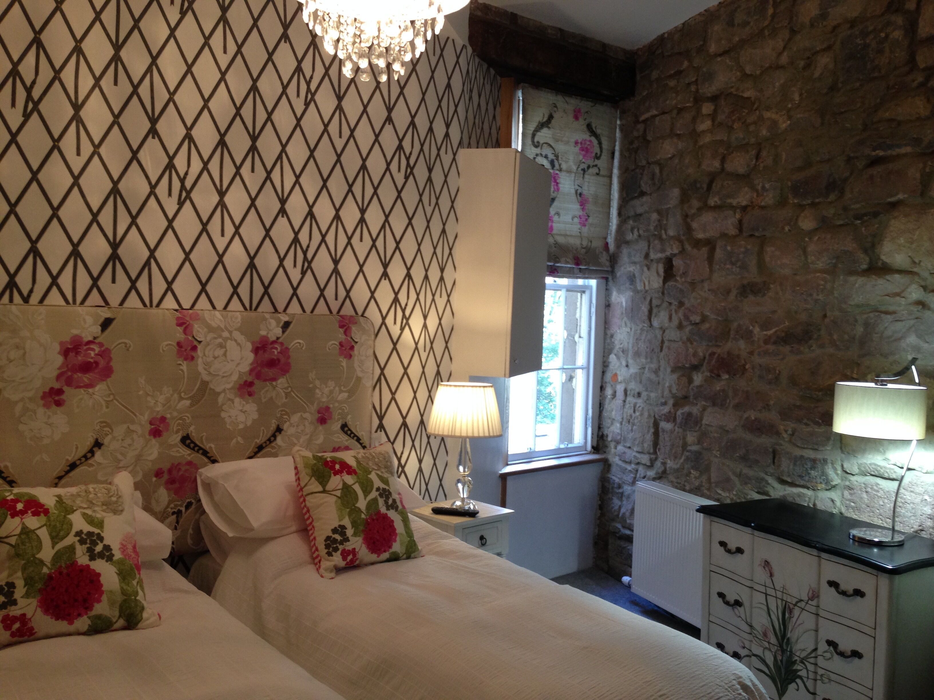 A bedroom with a bed, a nightstand, a lamp, and a dresser.