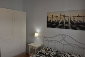 A bedroom with a bed, a nightstand, a lamp, and a wall-mounted painting of boats. - APARTMENT ON THE BEACH FANTASTIC VIEWS (Arona)