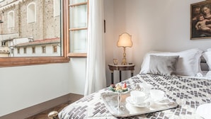Une chambre d’hôtel avec un lit, un plateau contenant des articles pour le petit-déjeuner, une lampe et un tableau au mur.