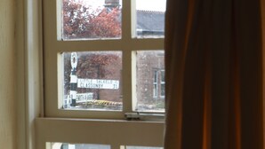 A window with a view of a street, a sign, and a vase with flowers. - The Shepherds Inn (Penrith)