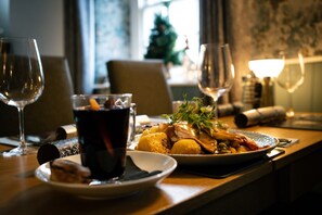 A dining table with a plate of food, a glass of red wine, and a candle. - The Shepherds Inn (Penrith)