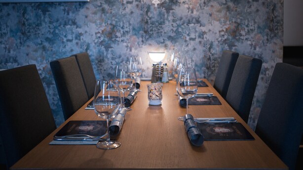 A dining table set for a meal with chairs, a decorative wall, and a snowflake light fixture. - The Shepherds Inn (Penrith)
