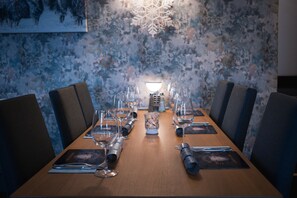 Ein Esstisch ist für eine Mahlzeit gedeckt, mit Stühlen, einer dekorativen Wand und einer Leuchte in Form eines Schneeflockens.