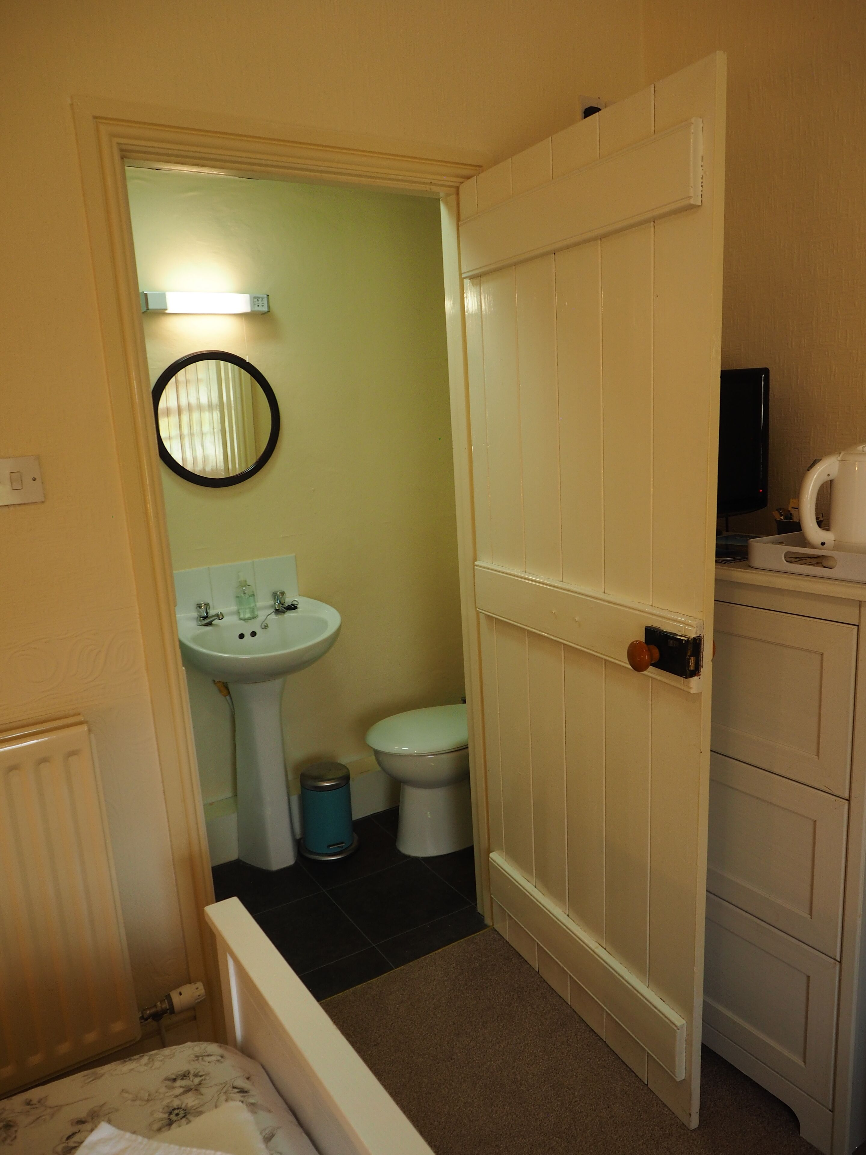 A small bathroom with a toilet, sink, and mirror.