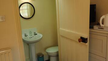A small bathroom with a toilet, sink, and mirror.