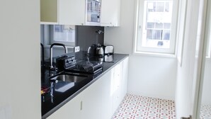 A modern kitchen with white cabinets, a black countertop, and a window with a view.