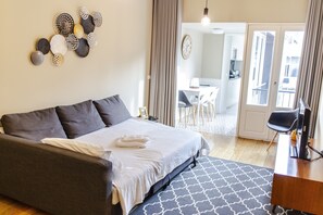 A modern hotel room with a large bed, a desk, and a view of the dining area. - Clérigos - One bedroom apartment (Oporto)