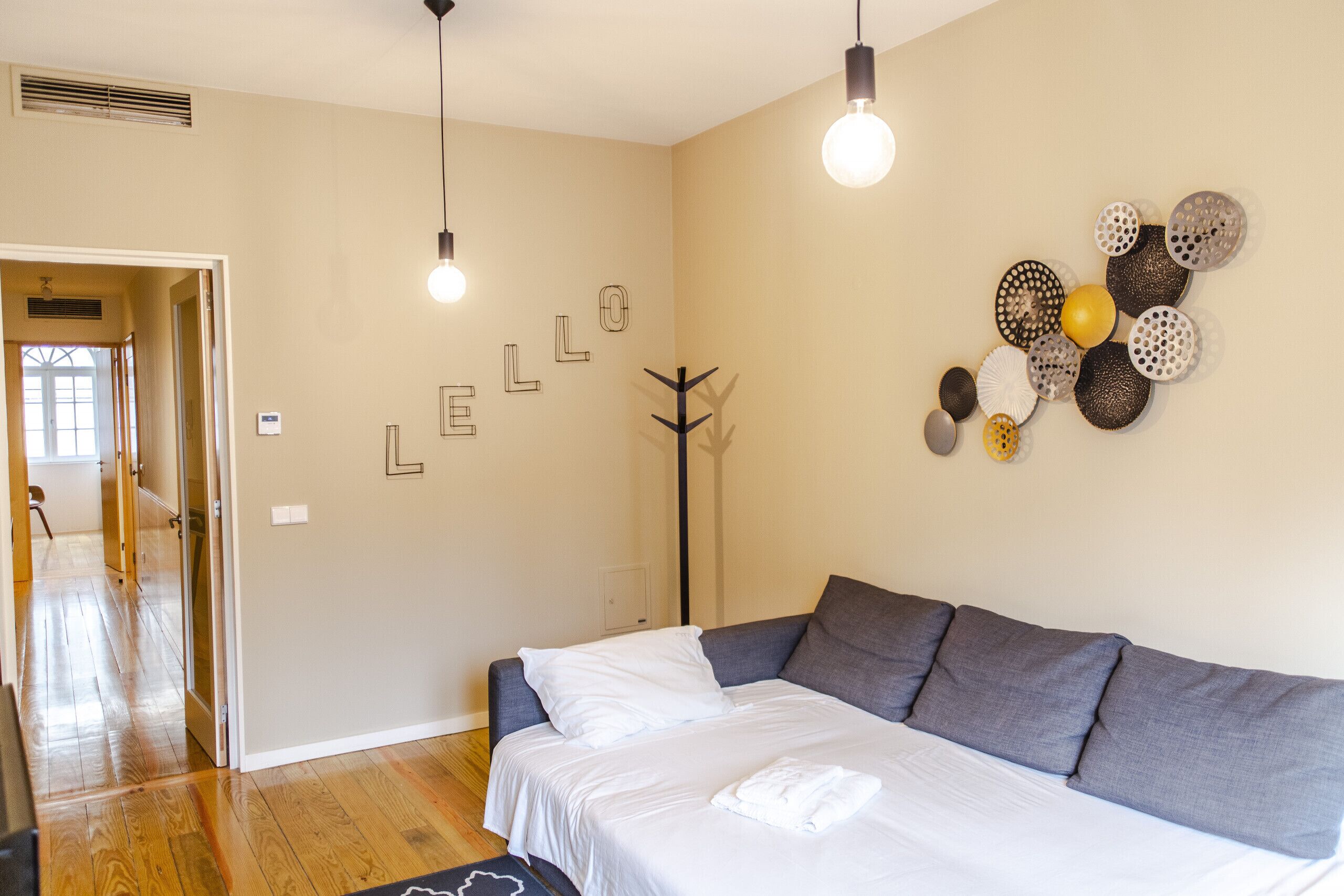 A bedroom with a bed, a coat rack, and a wall with decorative items.