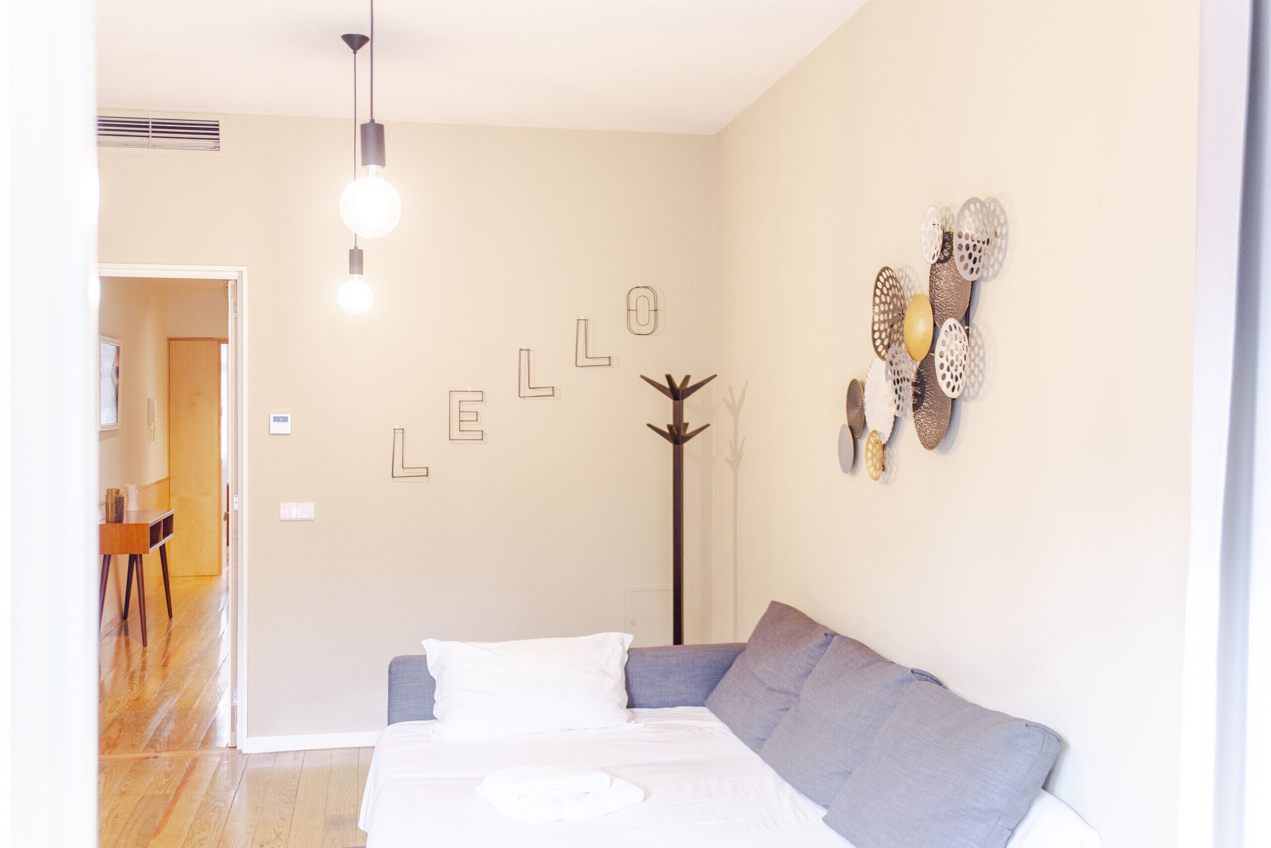 A bedroom with a bed, a sofa, a coat rack, and wall decorations.