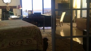 Ein Schlafzimmer mit einem großen Bett, einem Schreibtisch und einem Stuhl. Ein Fenster bietet Blick auf das Meer.