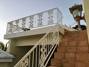 A staircase with ornate white railings leading to a balcony with decorative metalwork.
