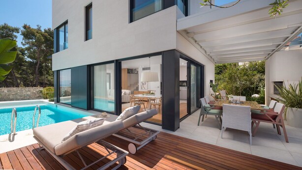 Una casa moderna con piscina, zona de estar exterior y porche cubierto.