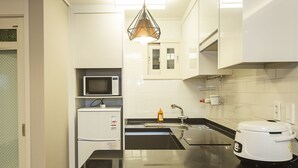 A modern kitchen with a microwave, sink, and a rice cooker.