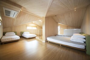 A spacious attic bedroom with wooden floors and sloped ceilings, featuring two single beds and a larger bed. - Eunbille (Seogwipo)